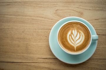 Hot coffee latte with latte art milk foam in cup mug on wood desk on top view. As breakfast In a coffee shop at the cafe,during business work concept