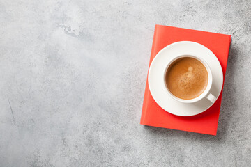 Book and cup of coffee on concrete surface