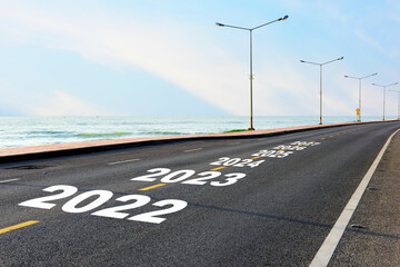 New year 2022 to 2027 on asphalt road with marking line for given direction and sea landscape....