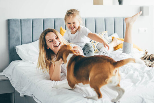 Happy mother and daughter having fun and playing together on the bed at home.