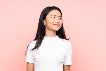 Fototapeta premium Teenager Chinese woman isolated on pink background looking side