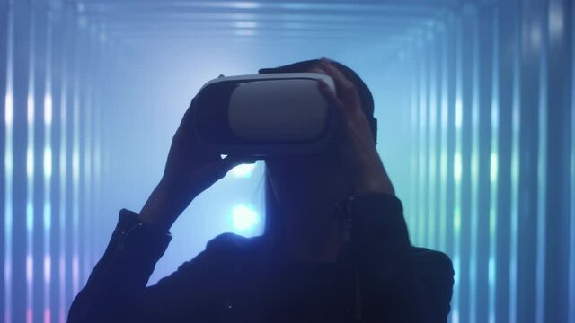 The girl holds virtual reality glasses in her hands, puts them on her head.