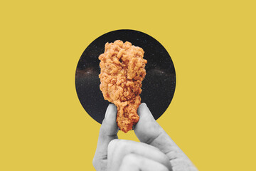 Hand holding fries chicken drumstick, on yellow background