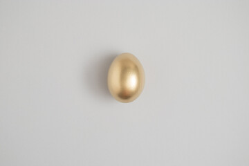 Gold easter egg on a gray background. Minimal holiday concept. Flat lay, top view.
