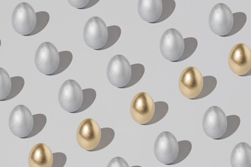 Pattern made of silver and gold easter egg on a gray background. Minimal holiday concept.