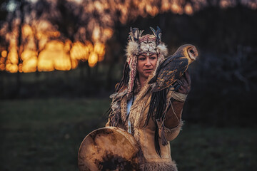beautiful shamanic girl playing on shaman frame drum in the nature.