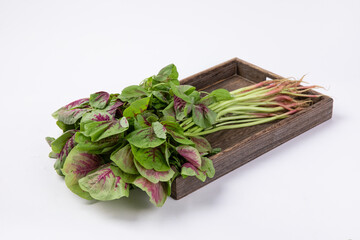 Closeup shot of chinese spinach on a wooden tray against a white background