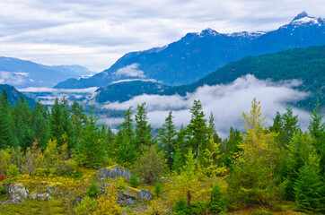 Fototapeta na wymiar A beautiful view with cloudy sky with foggy mist around the mountains and trees in a beautiful and peaceful rural country scene.