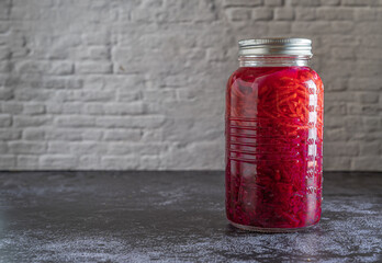 Dark moody food photography of a jar with homemade fermented red cabbage chucrut. Still life image with copy space.