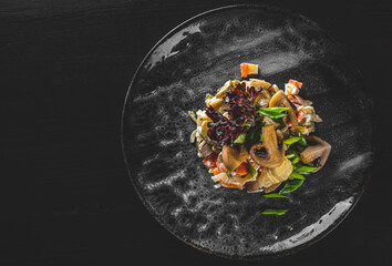 Gherkins, mushrooms, onion and cheese salad in plate on black wooden table background