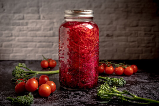 Dark moody food photography of a jar with homemade fermented red cabbage chucrut and vegetables. Still life image with a vintage look.