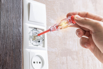 handyman repair wall light switch at apartment. worker using voltage electric tester pen to check power switch. electrician service concept