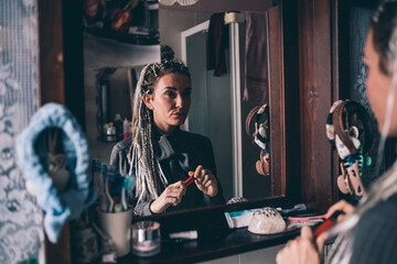 Adult caucasian woman indoor at home in bathroom putting lipstick on