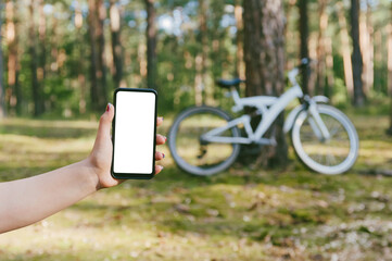Phone mockup in the girl's hand. Against the backdrop of nature bike and forest.