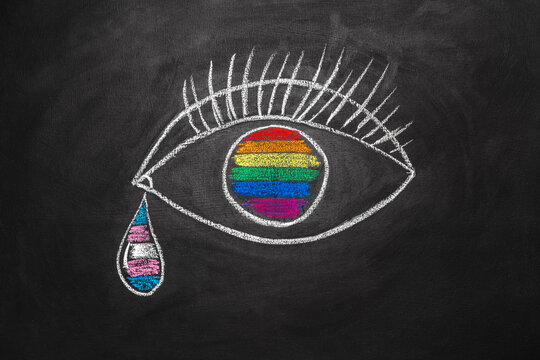 An eye is drawn on a chalkboard with an LGBT flag reflected in its pupil