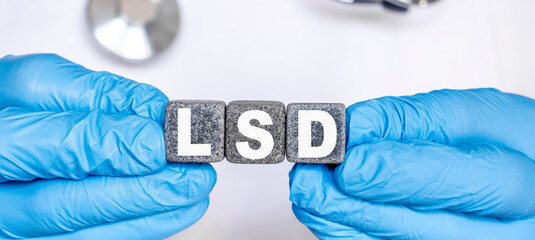 LSD Lysergic acid diethylamide - word from stone blocks with letters holding by a doctor's hands in...