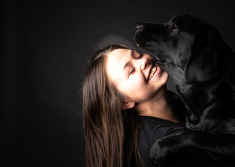 A girl holds a Labrador Retriever dog in her arms.