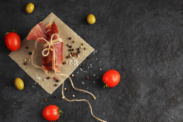 Organic homemade food. Pieces of spicy jerky tied with twine on parchment paper against a dark...