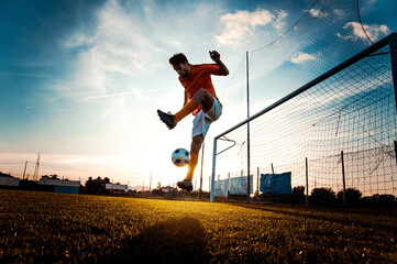 Soccer player in action on the soccer stadium - Man playing football on sunset - Football and sport championship concept