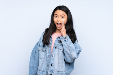 Teenager Chinese woman isolated on blue background with surprise and shocked facial expression