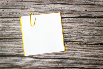 a stack of small blank sheets under a paper clip on a wooden background