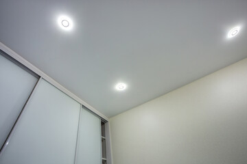 suspended ceiling with halogen spots lamps and drywall construction in empty room in apartment or house. Stretch ceiling white and complex shape.