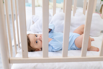 baby boy in crib in blue bodysuit, cute little baby in bedroom