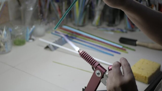 making glass products, the master takes a glass rod in his hands and heats it over the burner 4K video