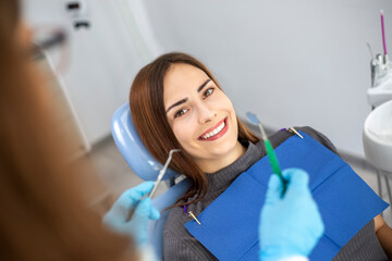 Dentist doctor treats a patient in a clinic. Young woman with white and healthy teeth.