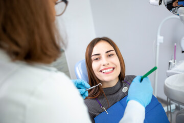 Dentist doctor treats a patient in a clinic. Young woman with white and healthy teeth.