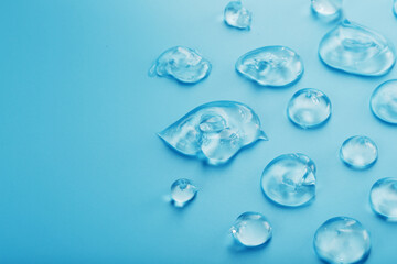 Drops of Gel with hyaluronic acid in the form of a smear of glossy texture on a blue background.