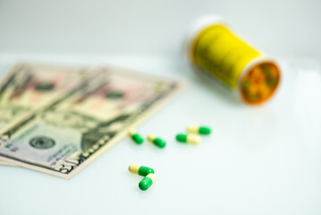 image of prescription capsule, tablets with US cash, currency intentional out of focus in background and bottle of pills. Medical concept. 