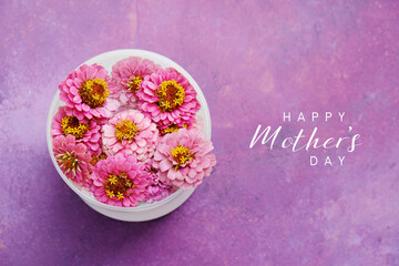 Naklejka premium Top view of zinnia flowers on purple background with Happy Mothers day text for holiday decorative banner.