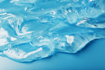 Gel with hyaluronic acid in the form of a smear of glossy texture on a blue background.