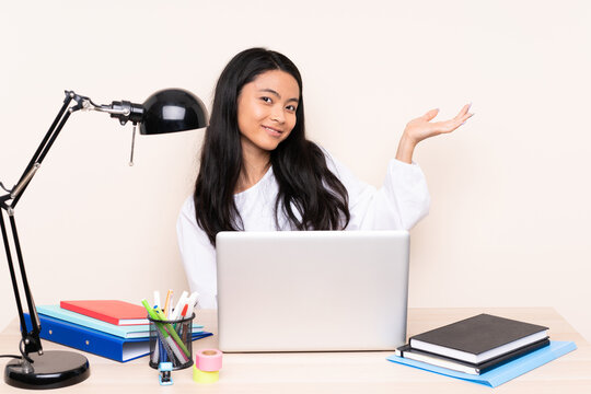 Student asian girl in a workplace with a laptop isolated on beige background extending hands to the side for inviting to come