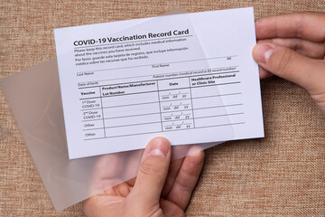 A man's hands are trying to laminate a vaccination record card certificate.