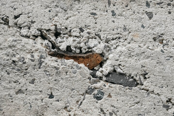 Gray old concrete surface with cracks and stones as a background texture.