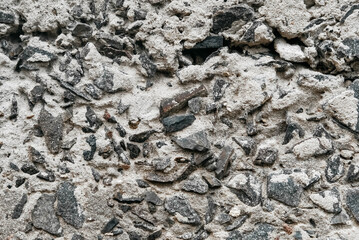 Gray old concrete surface with cracks and stones as a background texture.