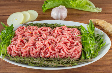 minced meat with greens and spices in a plate on a wooden table