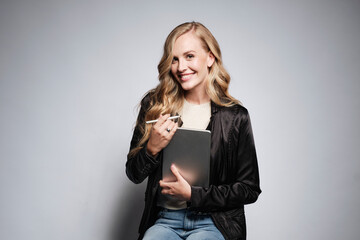 Portrait of an executive pretty blonde woman with her tablet while seated on a stool