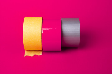 Three rolls of duct tape on a pink background.