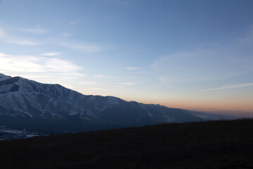 Landscape in the mountains at sunset. View of the misty hills hidden behind the oncoming darkness