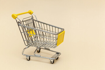 Metal shopping cart on a beige background.