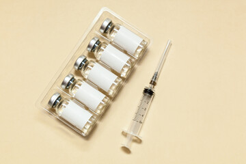Syringe with a vaccine on a beige background