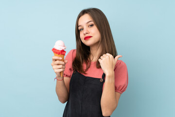 Teenager girl holding a cornet ice cream isolated on blue background pointing to the side to present a product