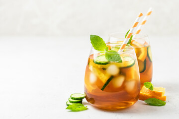 Honey mint cucumber orange iced tea in glasses. Space for text.