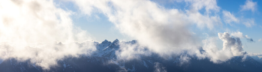Panoramic view of Rugged Mountain Peaks Covered in Snow and Clouds in Canadian Nature Landscape. Taken in Squamish, North of Vancouver, British Columbia, Canada.