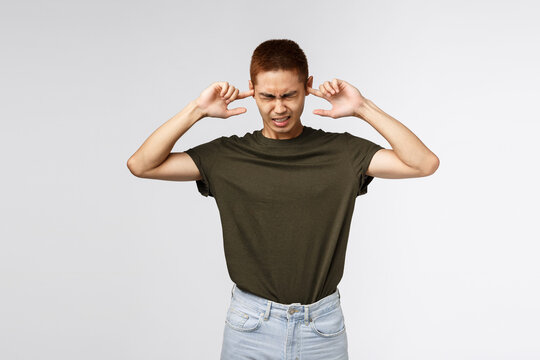 Cant Stand It Anymore. Portrait Of Annoyed Asian Guy Shut His Ears Irritated Over Noisy Music At Neighbours House, Sharing Flat With Loud Roommate, Grimacing Displeased, Grey Background