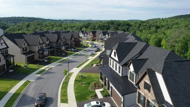 Flying over a curving street in a new development American neighborhood with luxury single family homes 