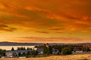 Sunrise over a small community next to the water, orange and yellow skies.